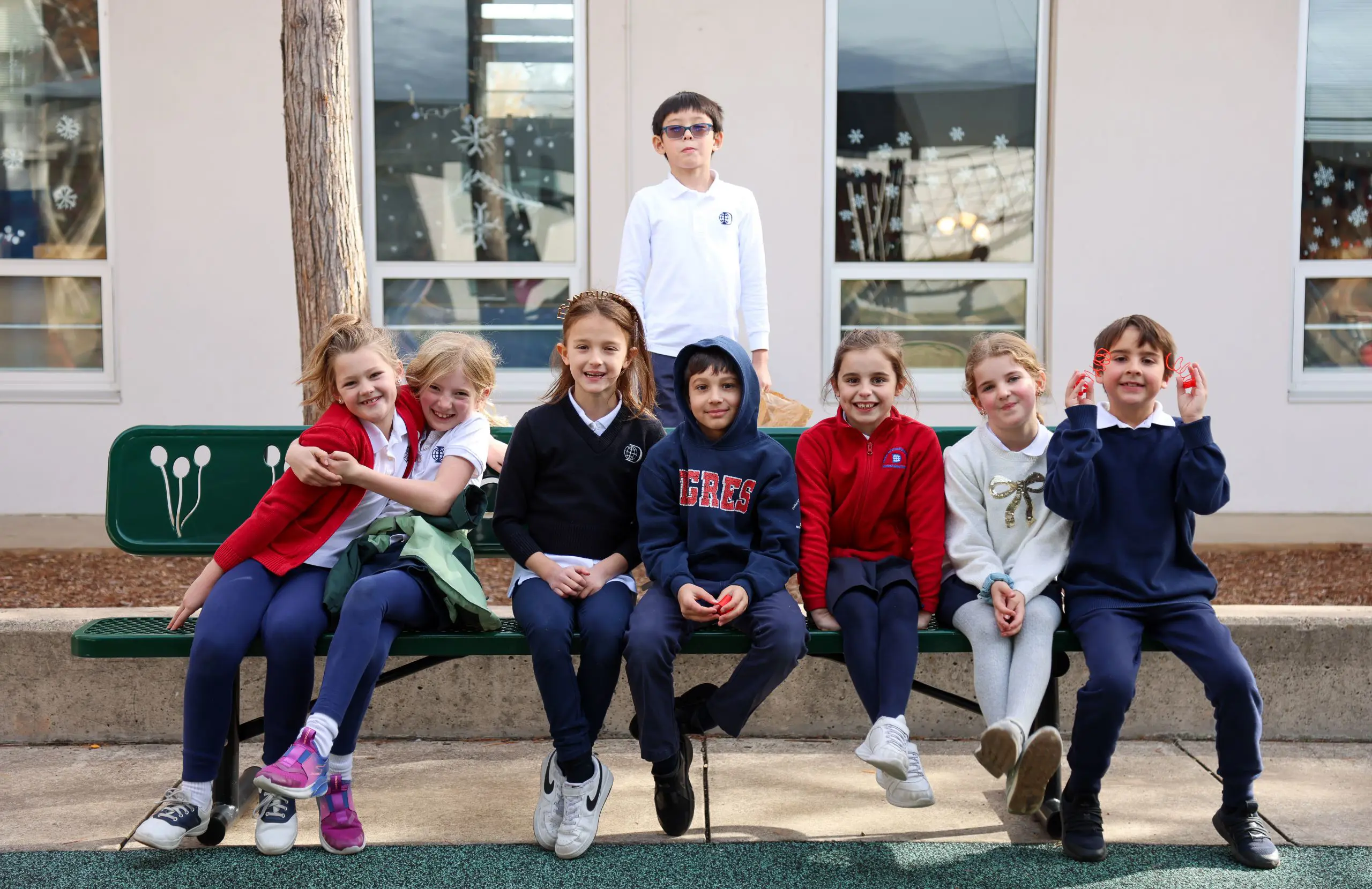DIS Elementary School students sitting together on a buddy bench in the playground at the Churchill Campus.
