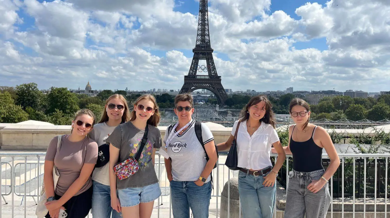 DIS High School Students and teacher stand in front of the Eiffel Tower on a school trip.