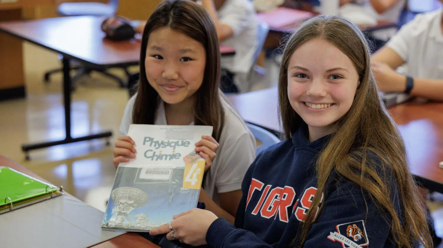 DIS High School students reading books and smiling.