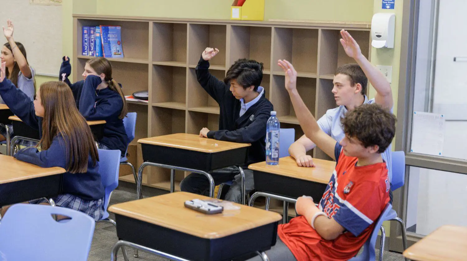 DIS High School student holding their hands up to answer a question in class.