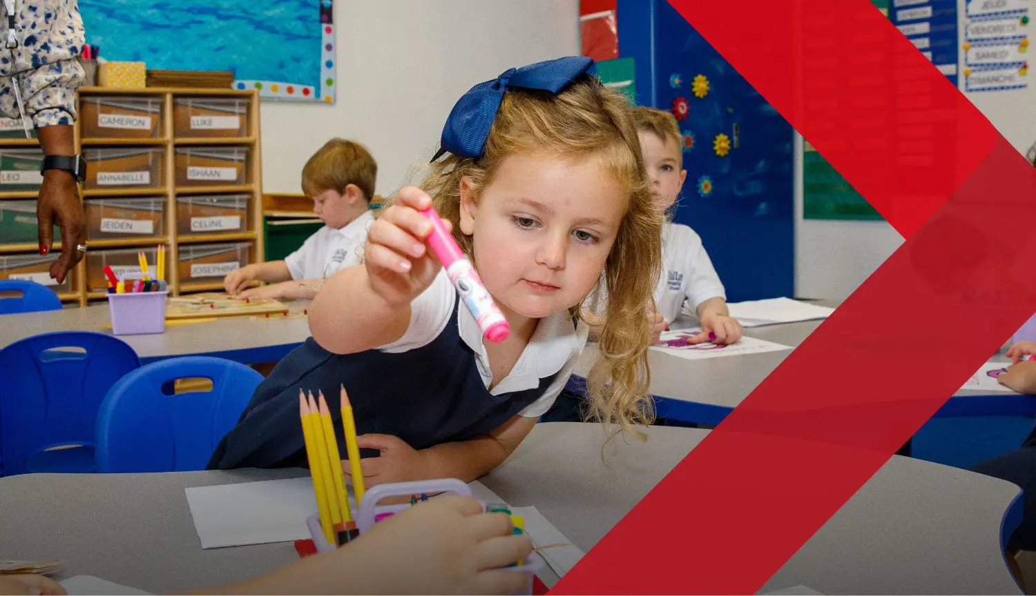 DIS Elementary school student putting a pen back into a pen pot while working on classwork.