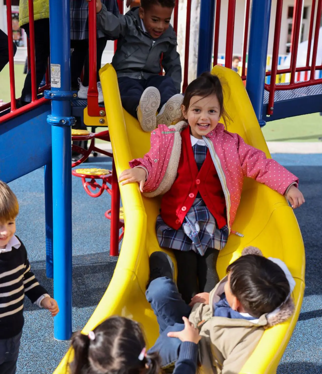 DIS Elementary school students playing on a slide at recess.