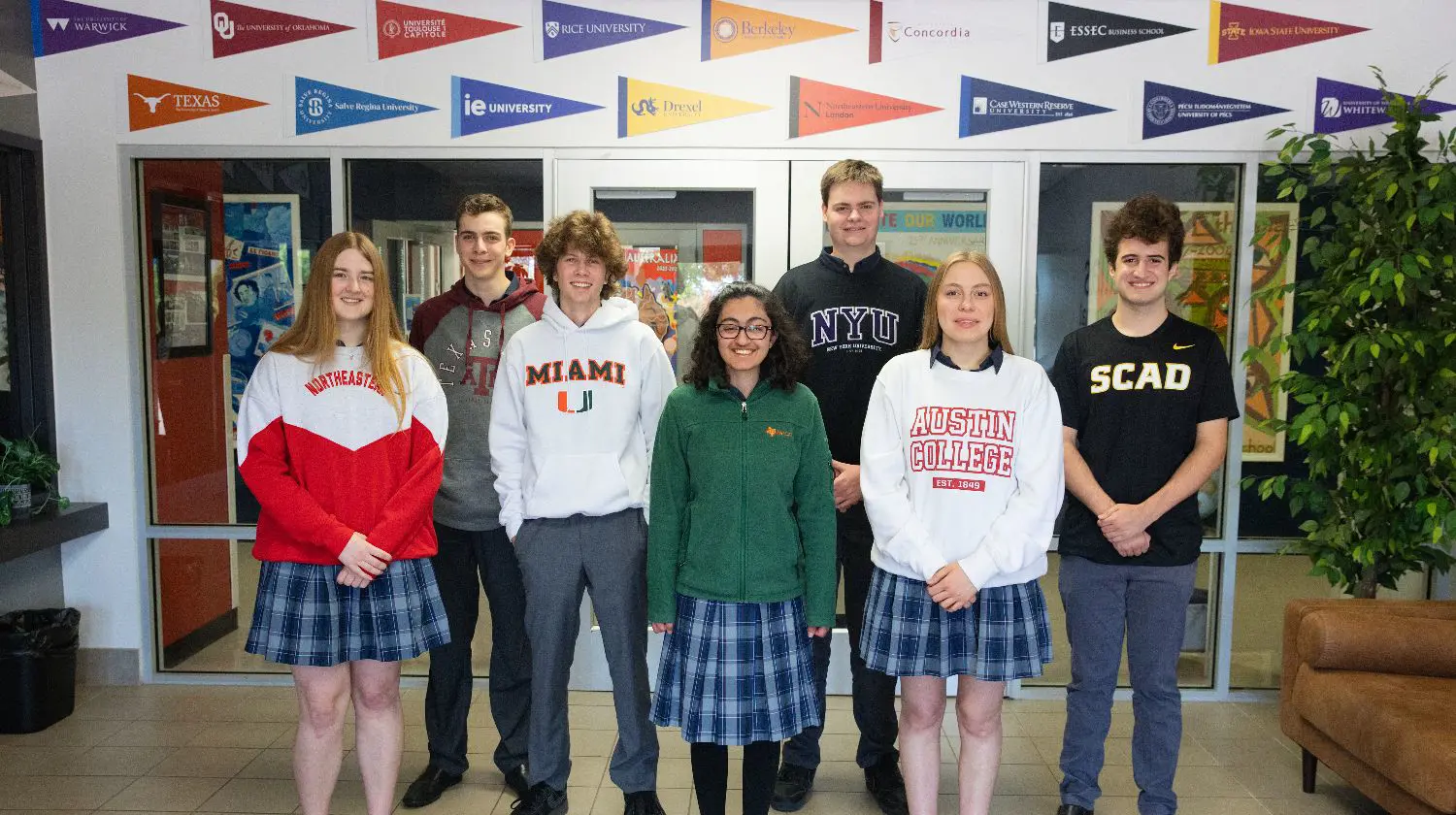 DIS High School Students wearing college sweaters and smiling.
