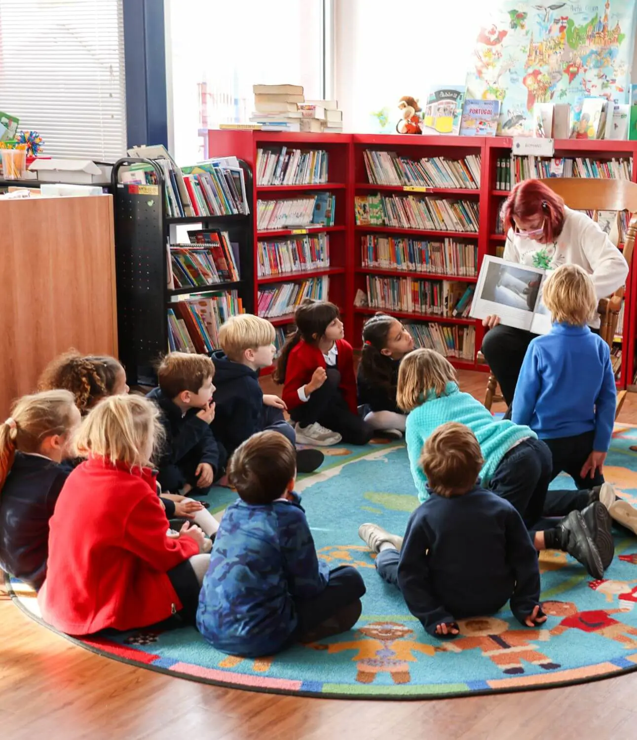 Teacher reading to early childhood students at DIS in the library.