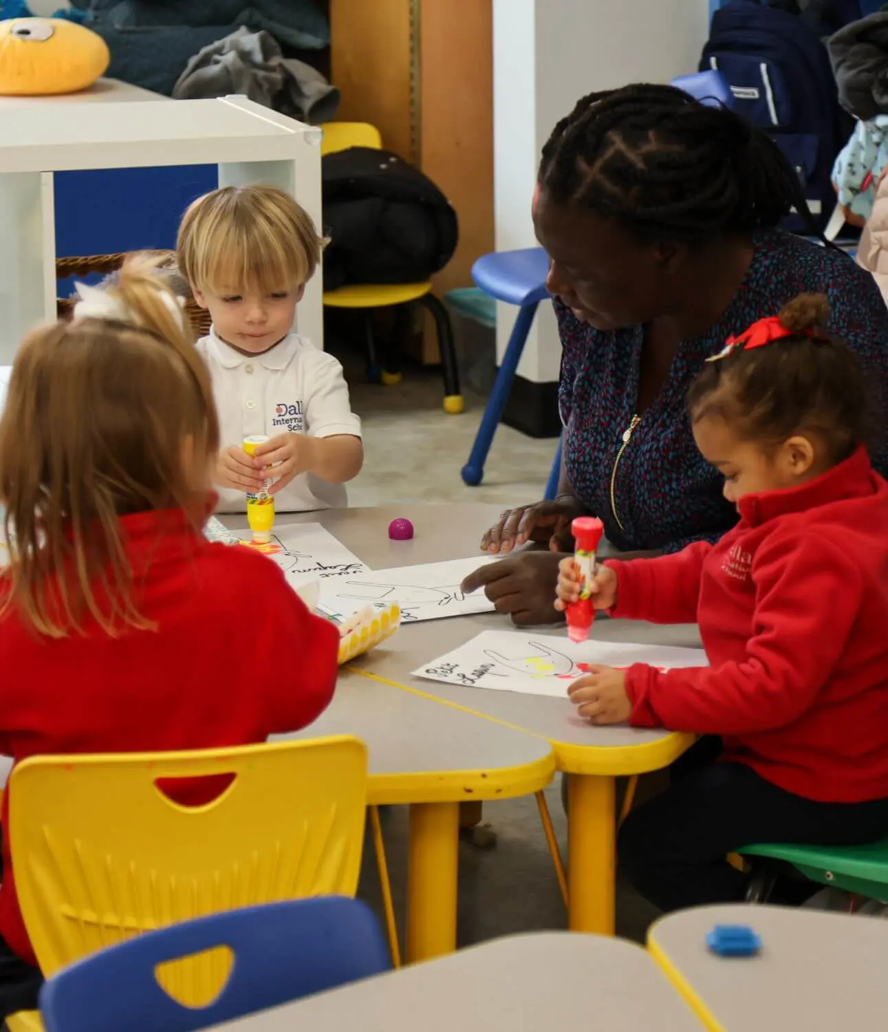 Teacher helping early childhood students with their classwork.