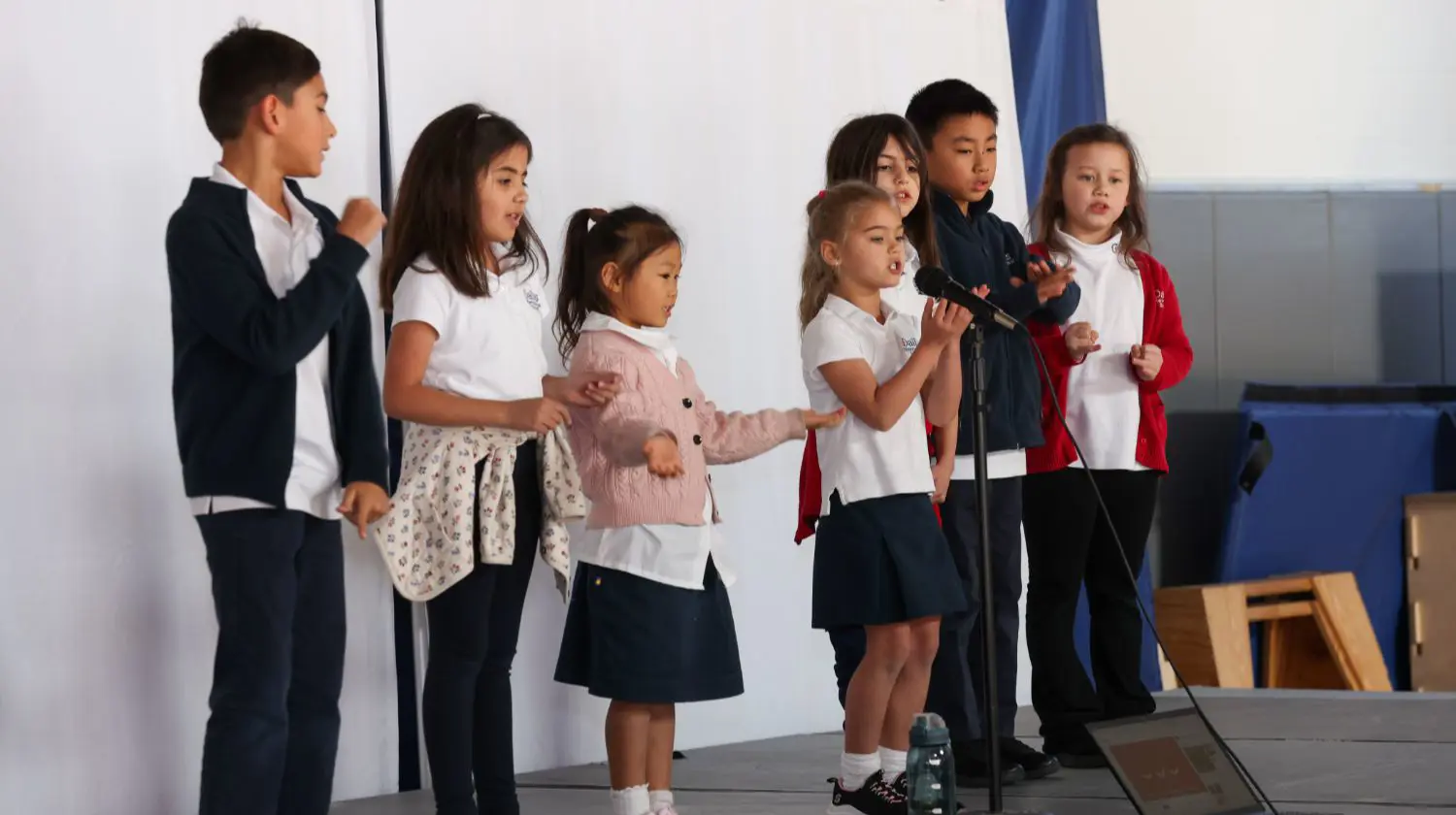 DIS elementary students performing on stage during an assembly.
