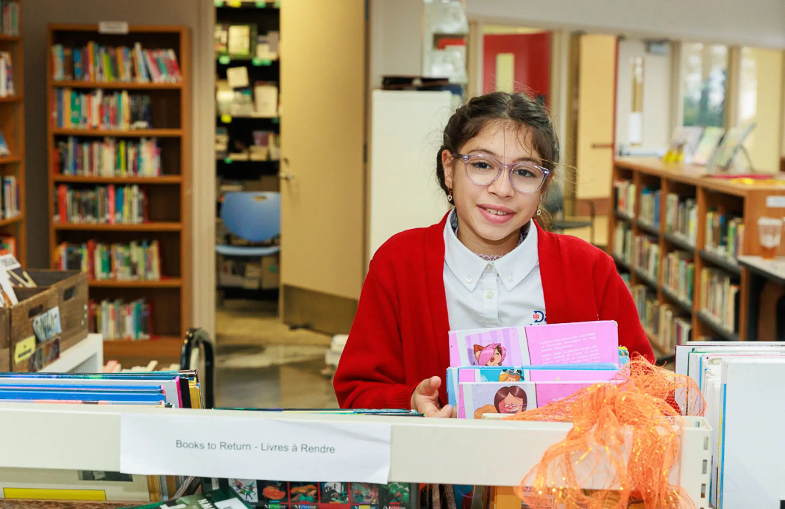 DIS middle school student smiling while selecting a book in the library.