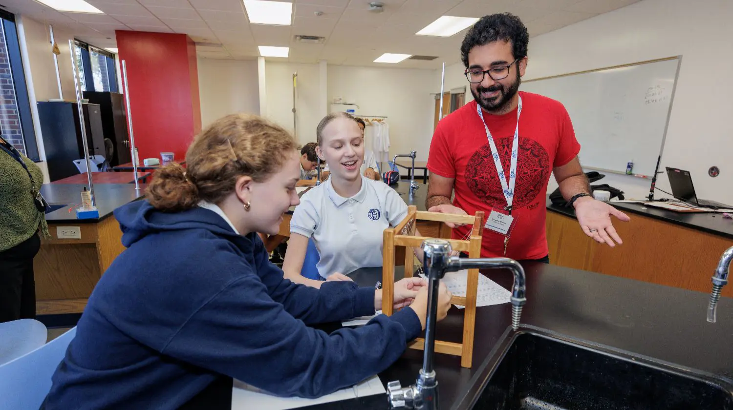 DI8S students and teacher studying a Newtons Cradle in a science class.