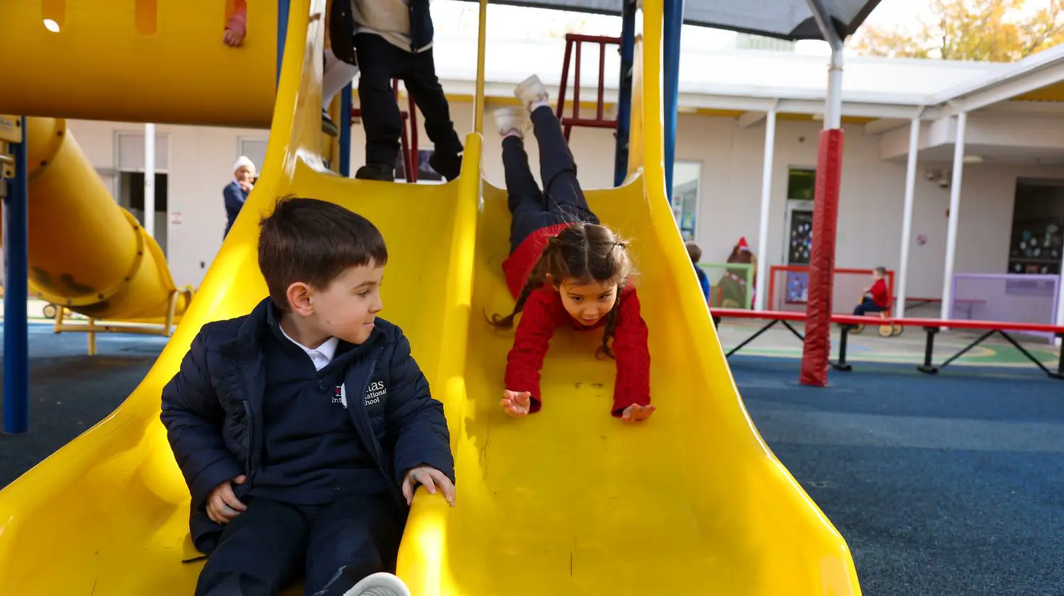 DIS elementary students playing on a slide at recess.