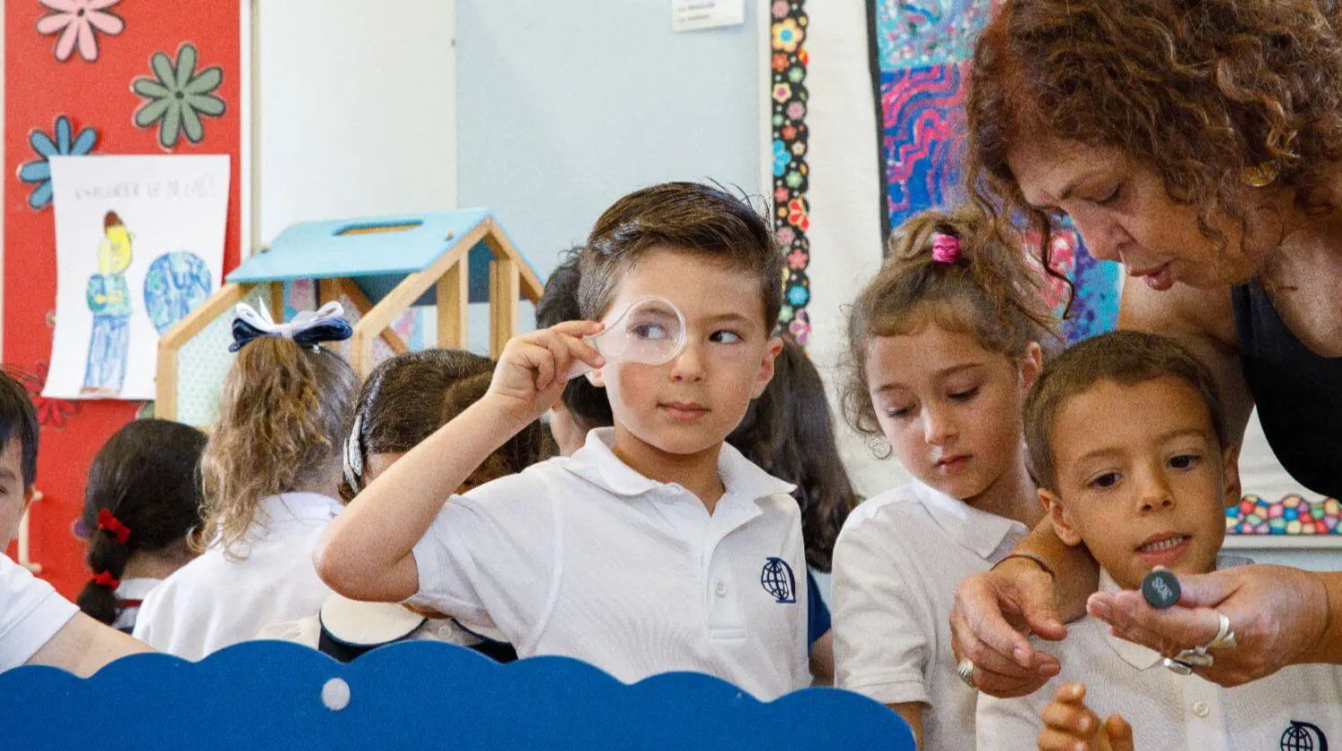 DIS EC Elementary School Student looking through a magnifying glass.