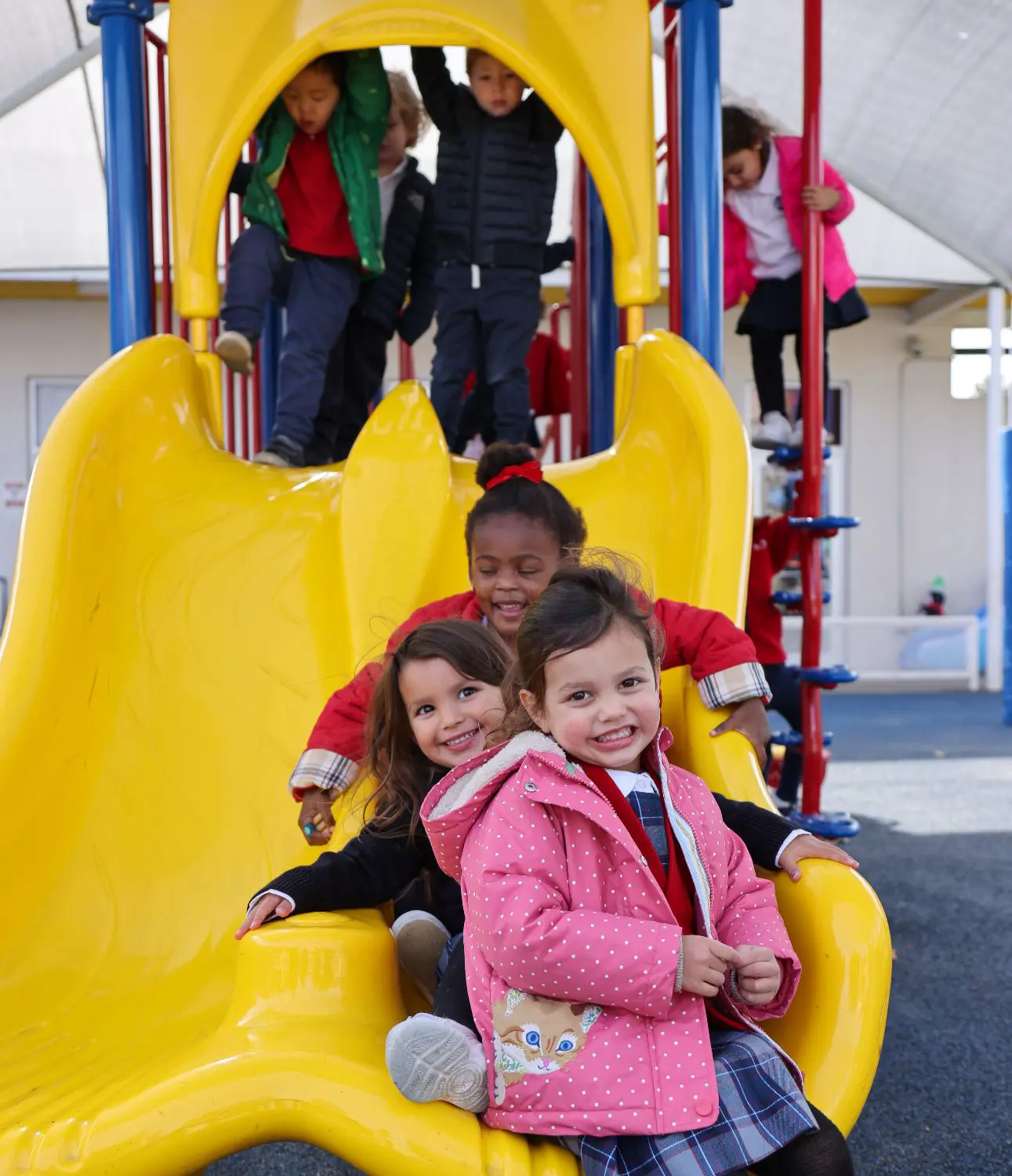 DIS Elementary School students playing on a slide in the playground.
