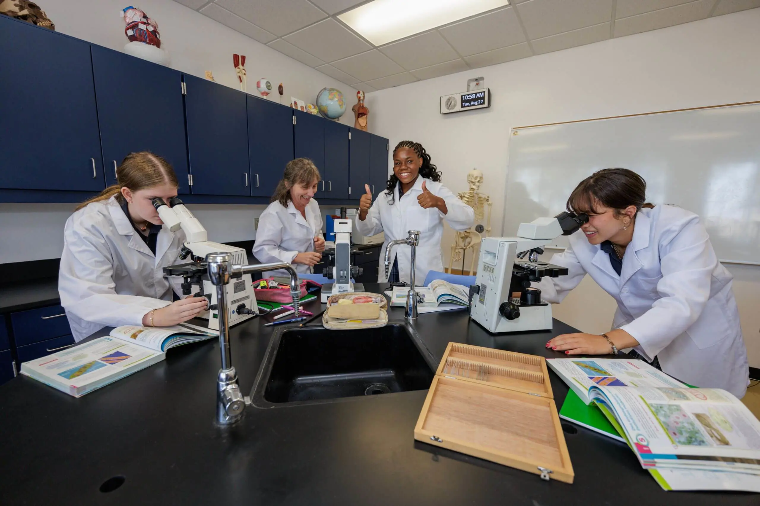DIS High School students working with microscopes together in a science class.