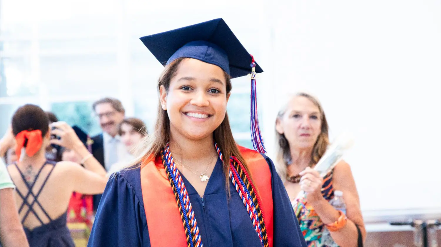 DIS High School student smiling for a photo at their graduation ceremony.