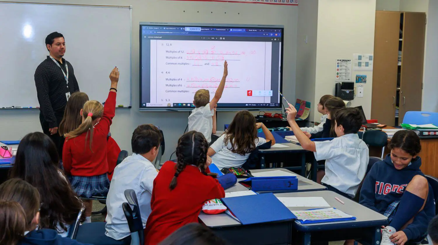 DIS students raise their hands in a class.