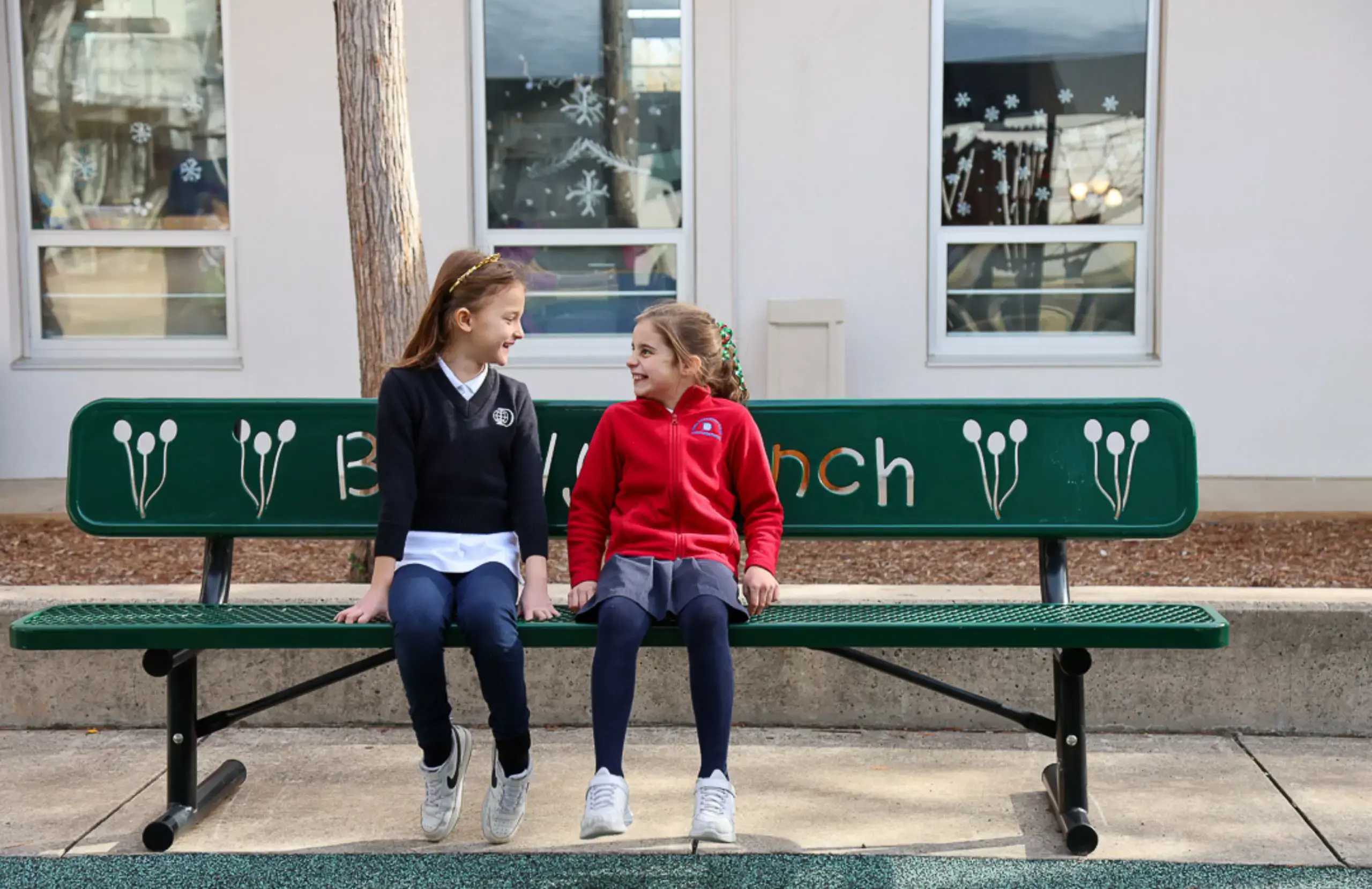 DIS Elementary School students sitting together on a buddy bench in the playground at the Churchill Campus.