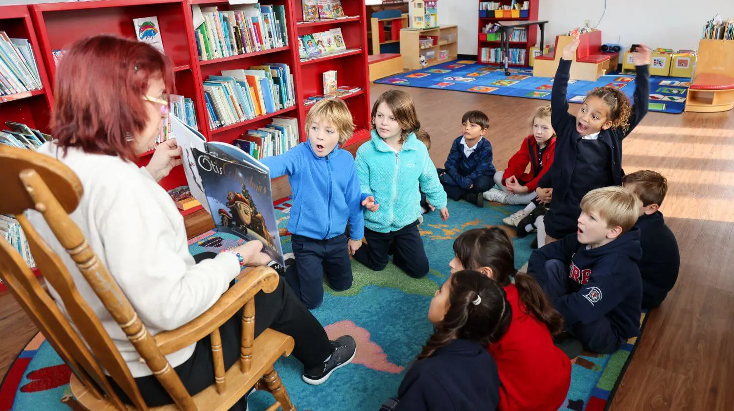 DIS teacher reading to elementary school students in the library.