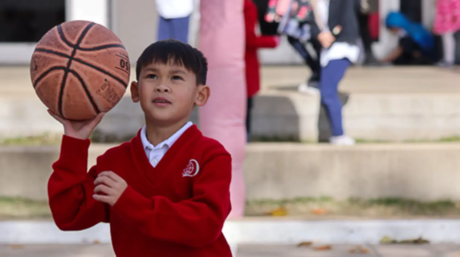DIS elementary student playing basketball in the playground.