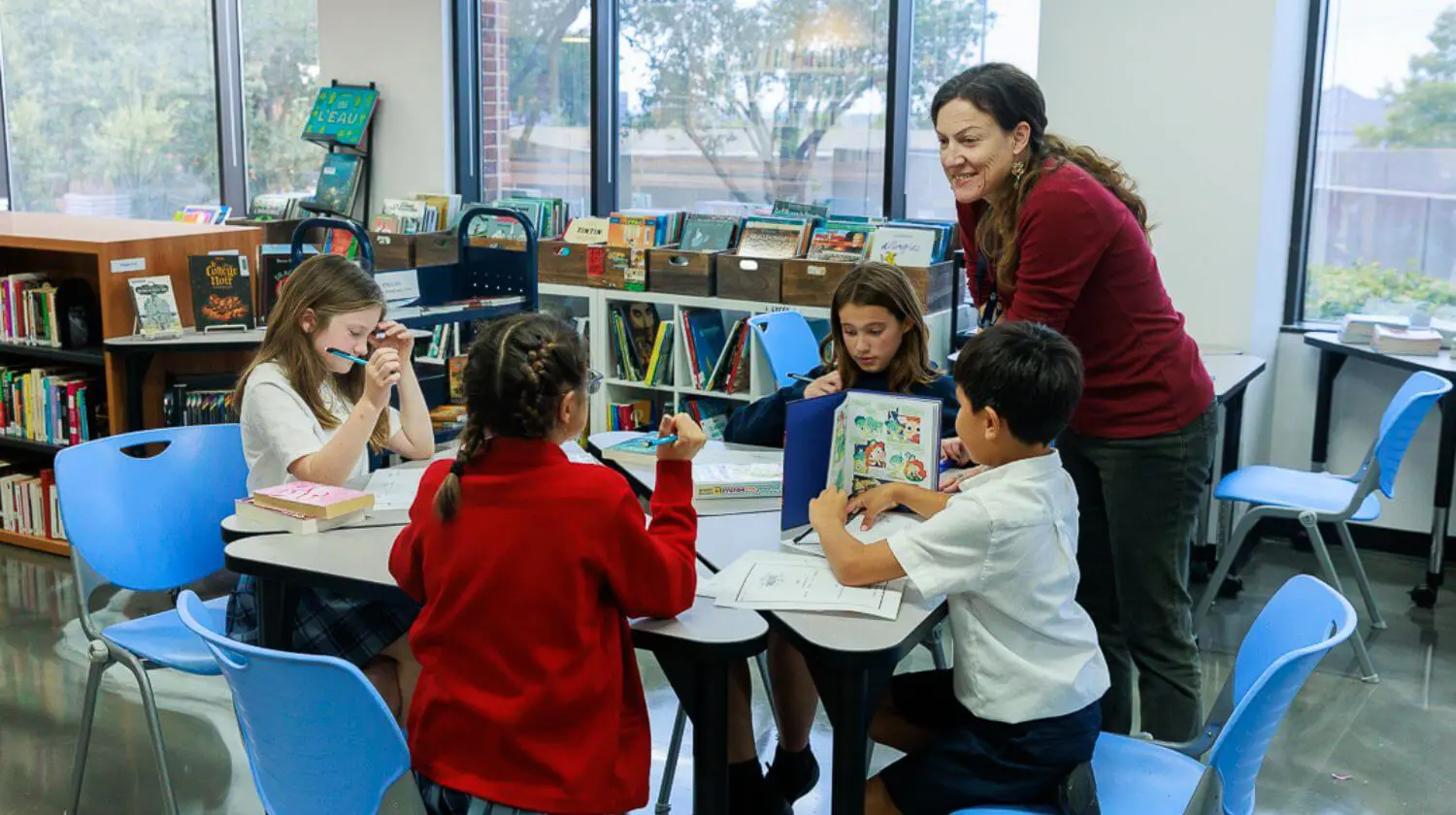  DIS students completing class work in the Library with the help of a teacher.